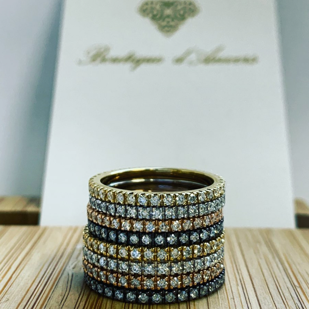 Stack of diamond-encrusted rings on a wooden surface with a blurred background