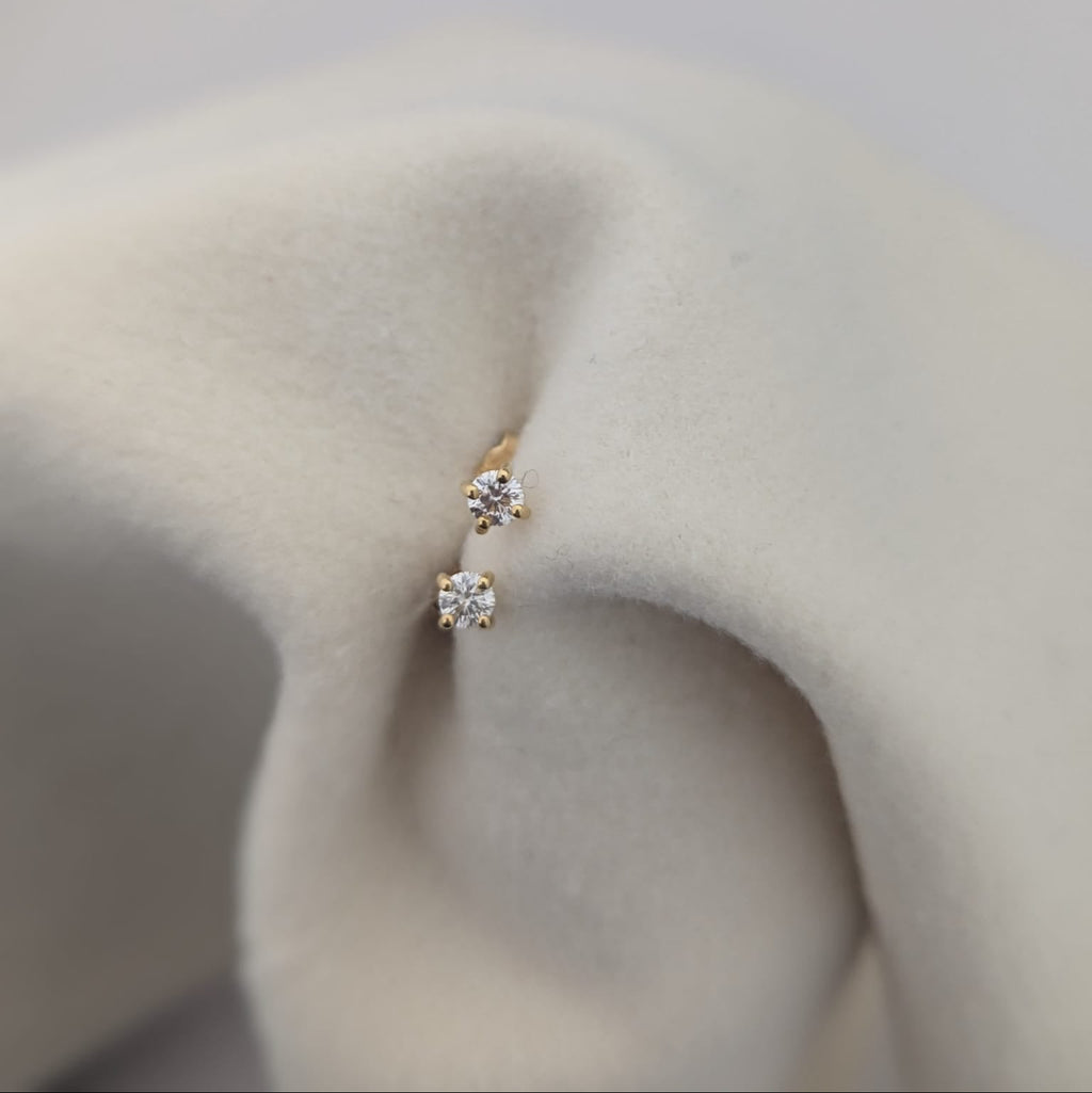 Gold earrings with clear stones on a soft beige fabric background