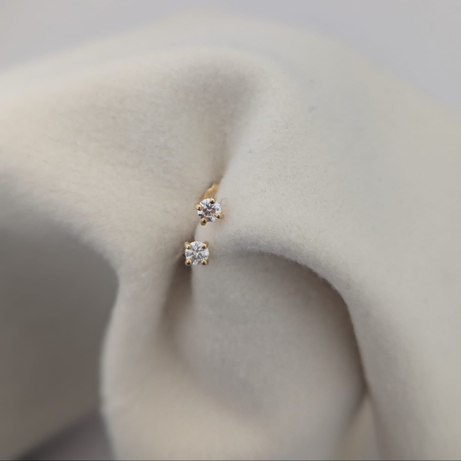 Gold earrings with clear stones on a soft beige fabric background